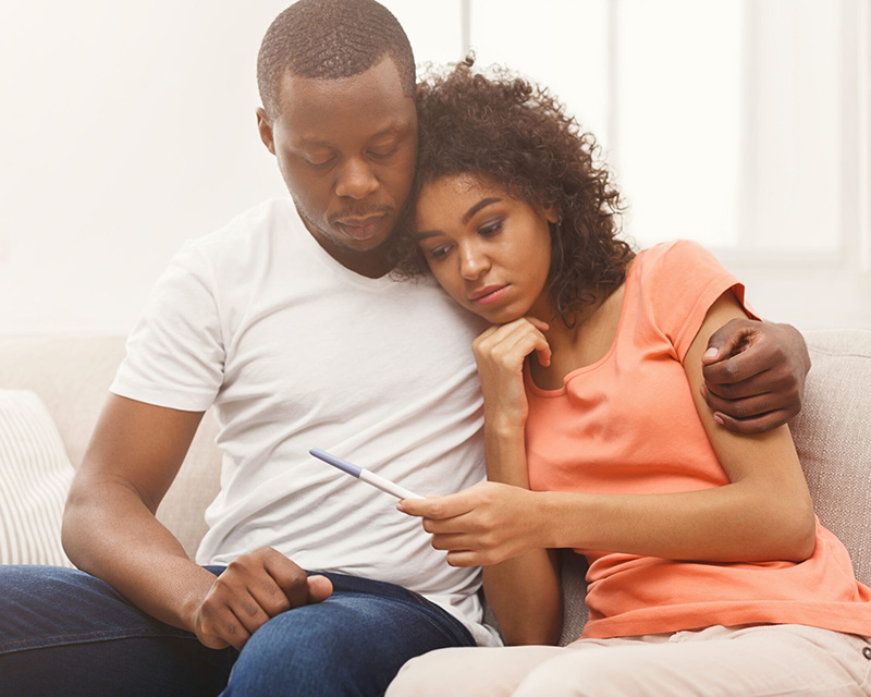 Black couple looking at a pregnancy test in need of couples therapy for infertility