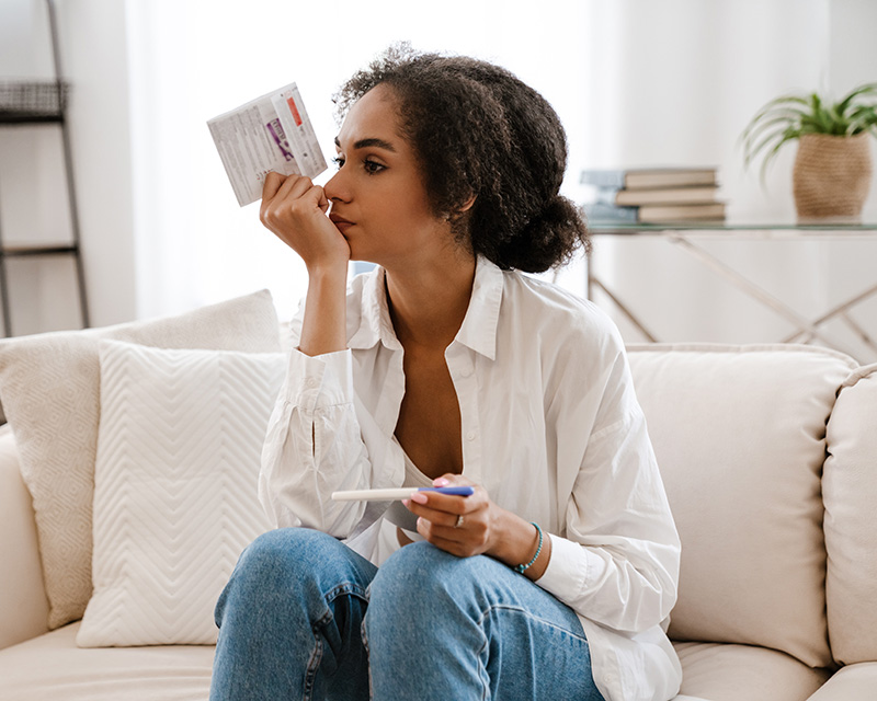 African American woman with pregnancy test, feeling frustrated with infertility