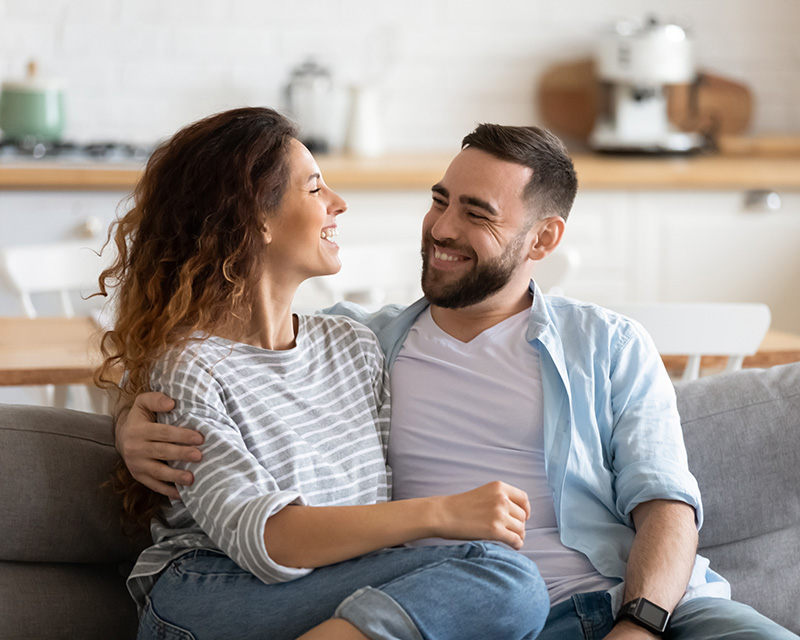 Couple looking at each other on the couch after online couples therapy for infertility